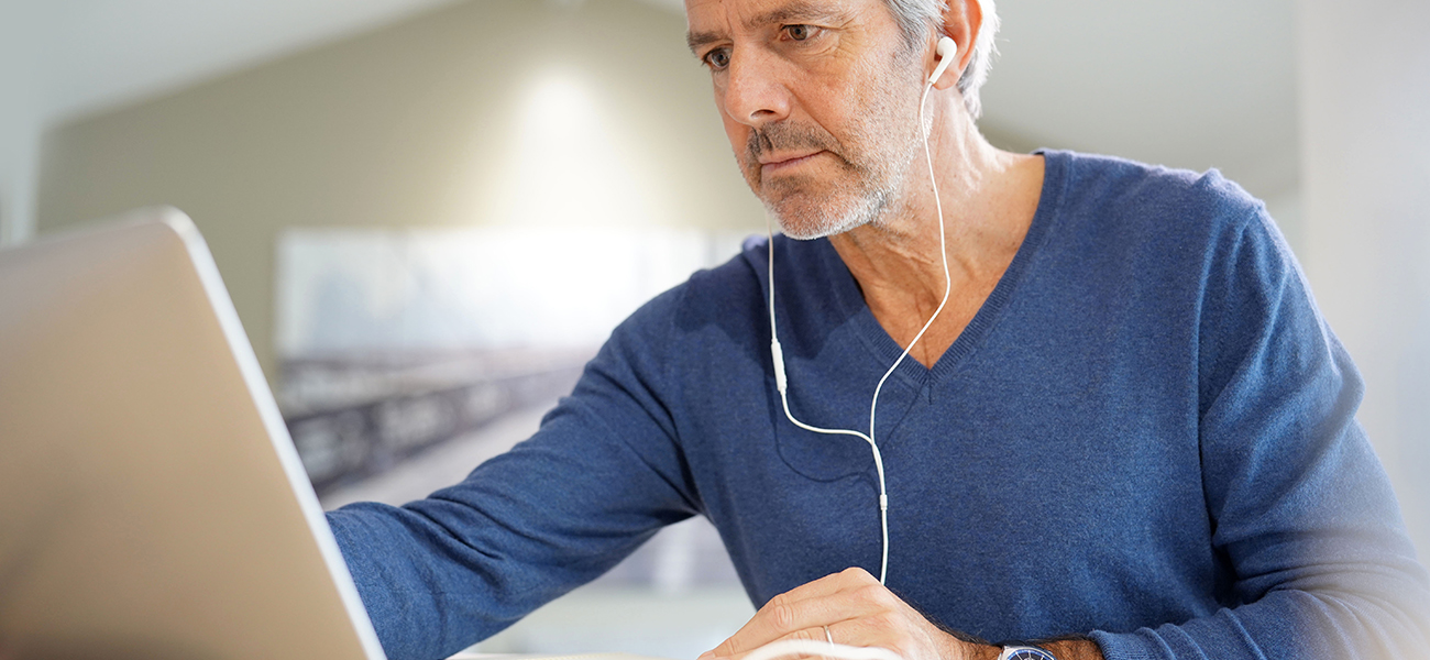 Middle aged man watching a virtual workshop on his laptop