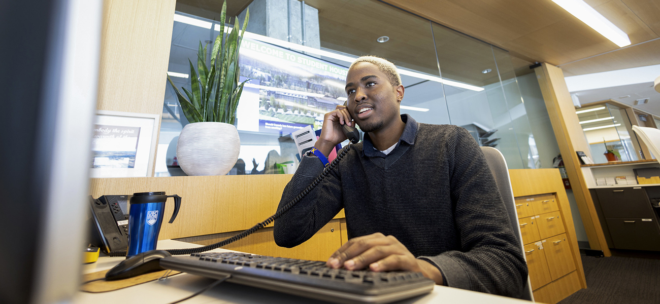 UBC staff member from the Okanagan campus at desk and on phone