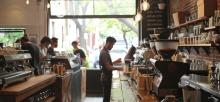 Busy coffee shop with patrons enjoying their drinks and barista crafting coffee