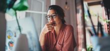 Woman contemplative while reading document on computer screen.