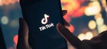 Hand holding phone with TikTok application loading